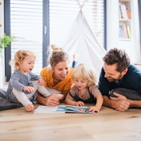 Young Family With Two Small Children Indoors In Bedroom Reading